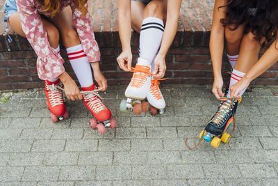 Hands of women tying laces of roller skates