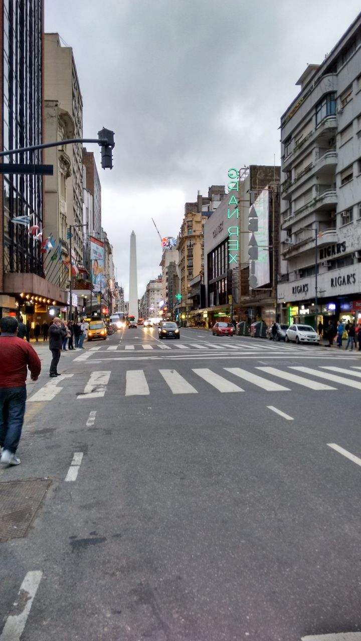 building exterior, architecture, built structure, city, street, transportation, car, road marking, sky, road, city street, land vehicle, the way forward, city life, incidental people, cloud - sky, building, mode of transport, diminishing perspective, outdoors