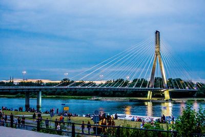 View of suspension bridge over river against cloudy sky