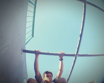 Low angle view of boy playing on monkey bars at park