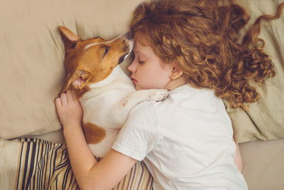 Sweet curly girl and jack russell dog is sleeping in night.