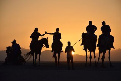 Silhouette people on beach against sky during sunset