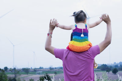 Rear view of woman with arms raised against sky