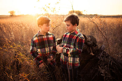 Siblings on field against sky