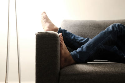 Low section of man relaxing on sofa