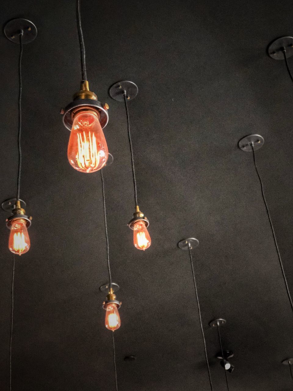 LOW ANGLE VIEW OF ILLUMINATED LIGHT BULBS HANGING ON CEILING