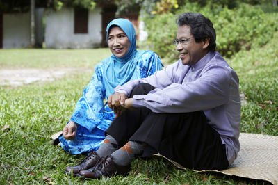 Happy couple sitting on grass in back yard