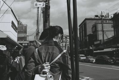 Rear view of man and woman standing by road in city