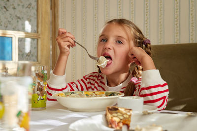 Hungry girl eats homemade dumplings dipped in sour cream