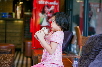 Side view of girl drinking coffee while sitting at cafe