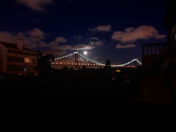 Illuminated bridge in city against sky at night