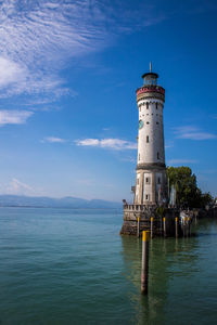 Lighthouse by sea against blue sky