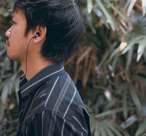 Side view of young man wearing in-ear headphones