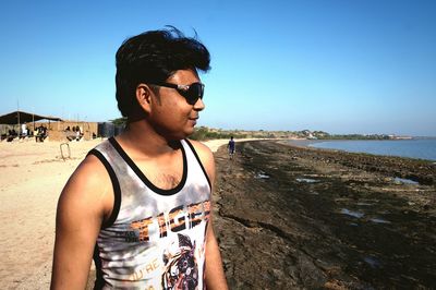 Young man wearing sunglasses standing on beach