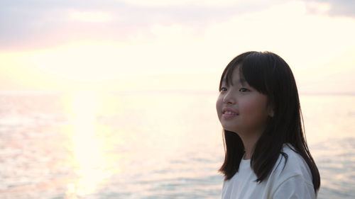 Portrait of woman standing at beach during sunset