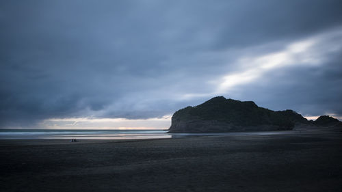 Scenic view of beach against sky at dusk