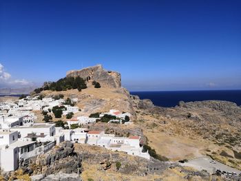 Townscape by sea against clear blue sky