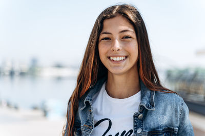 Portrait of smiling young woman standing against water