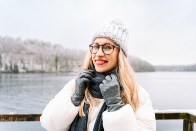 Portrait of young woman standing against lake