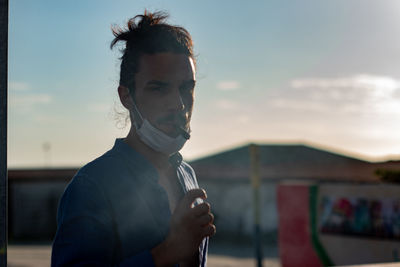 Portrait of young man standing against sky