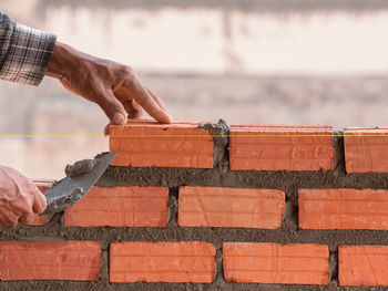 Man working on wood against brick wall