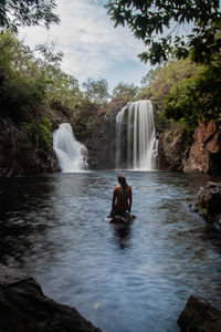 Man surfing on rock in waterfall