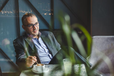 Businessman with coffee cup on table sitting in cafe