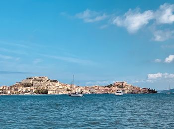 Buildings by sea against blue sky