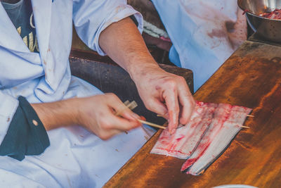 Midsection of chef preparing fish skewer in kitchen