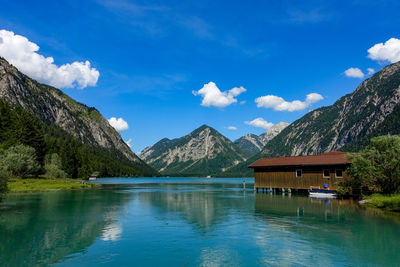 Scenic view of lake and mountains against blue sky