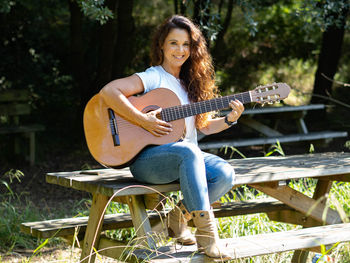 Full length of young woman playing guitar