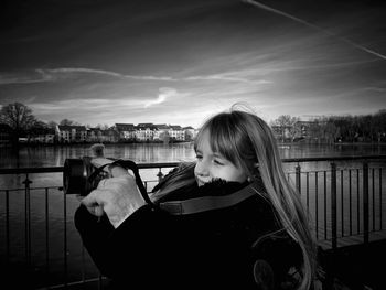 Portrait of woman against railing against sky