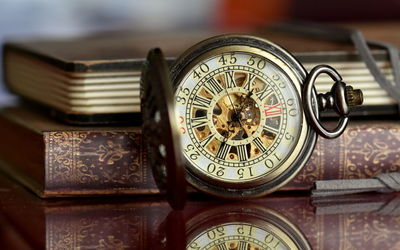 Close-up of pocket watch with books on table