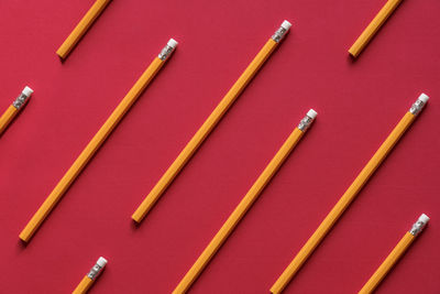High angle view of yellow pencils on red background