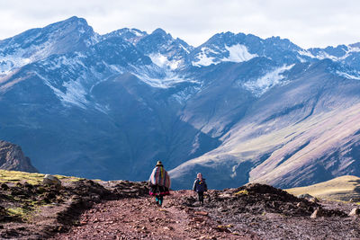 People on snowcapped mountains against sky