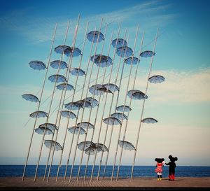 Rear view of people at beach against sky