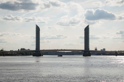 Tower bridge over river against sky in city