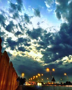 Illuminated city against cloudy sky