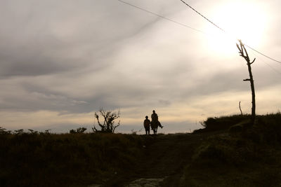 Silhouette man on land against sky during sunset
