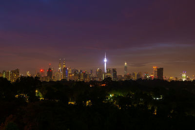 Illuminated buildings in city against sky at night