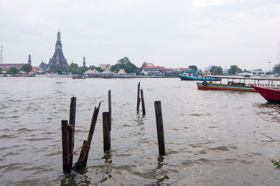 Wooden posts in sea against cloudy sky