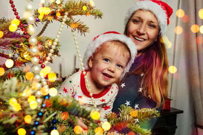Portrait of smiling woman with christmas tree at home