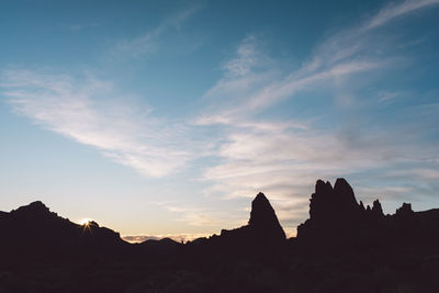 Silhouette rock formations against sky during sunset