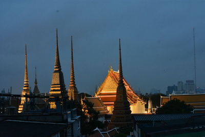 Temple amidst buildings in city at dusk