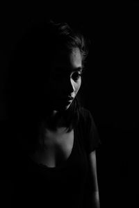 Close-up of young woman against black background