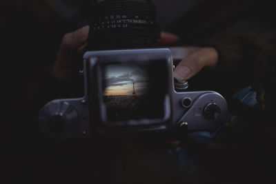 Cropped hands photographing eiffel tower during sunset