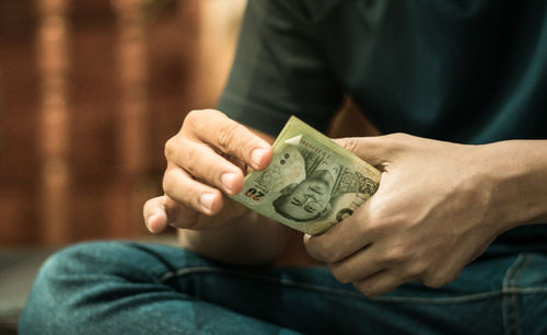 Midsection of man holding paper currency