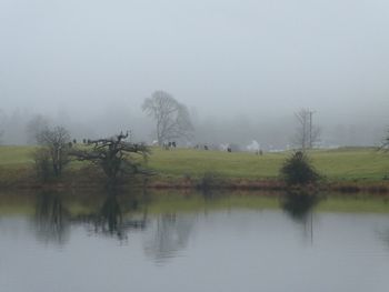 Scenic view of lake against sky during foggy weather