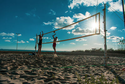 People playing beach volleyball against sky