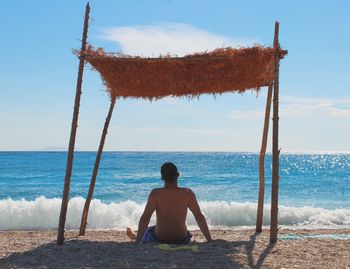 Rear view of woman sitting on beach